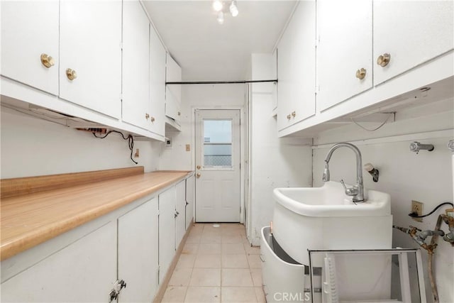 laundry area featuring light tile patterned floors and cabinets