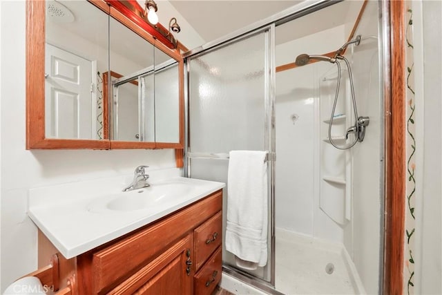 bathroom featuring a shower with door and vanity