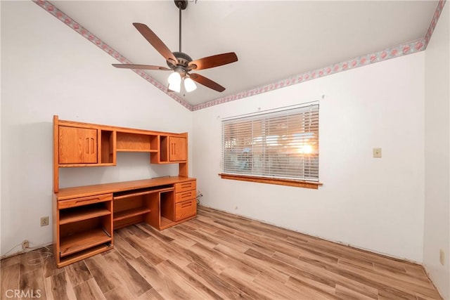 unfurnished office featuring ceiling fan, light hardwood / wood-style flooring, built in desk, and vaulted ceiling