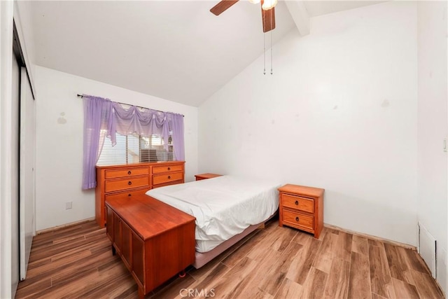 bedroom with ceiling fan, wood-type flooring, beam ceiling, high vaulted ceiling, and a closet