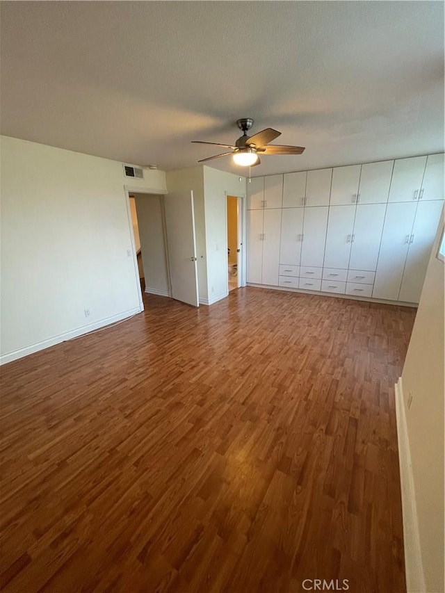 interior space featuring ceiling fan, wood-type flooring, and a textured ceiling