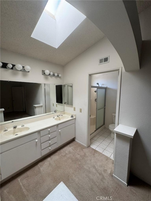 bathroom with an enclosed shower, vanity, a textured ceiling, lofted ceiling with skylight, and toilet