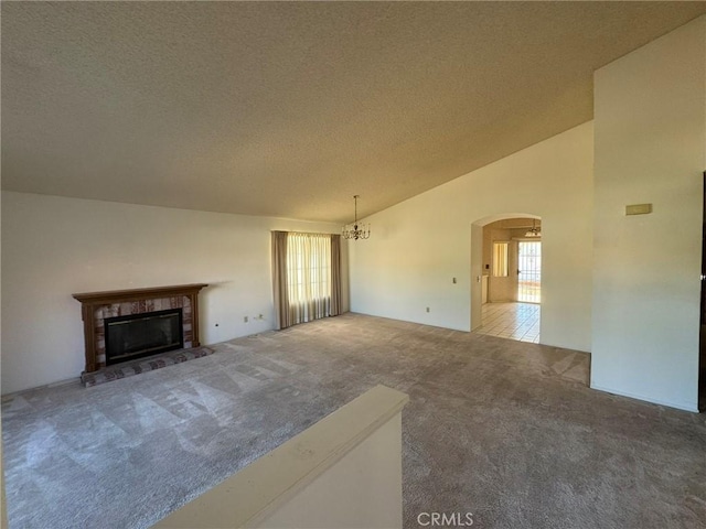 unfurnished living room with carpet, lofted ceiling, a wealth of natural light, and a fireplace