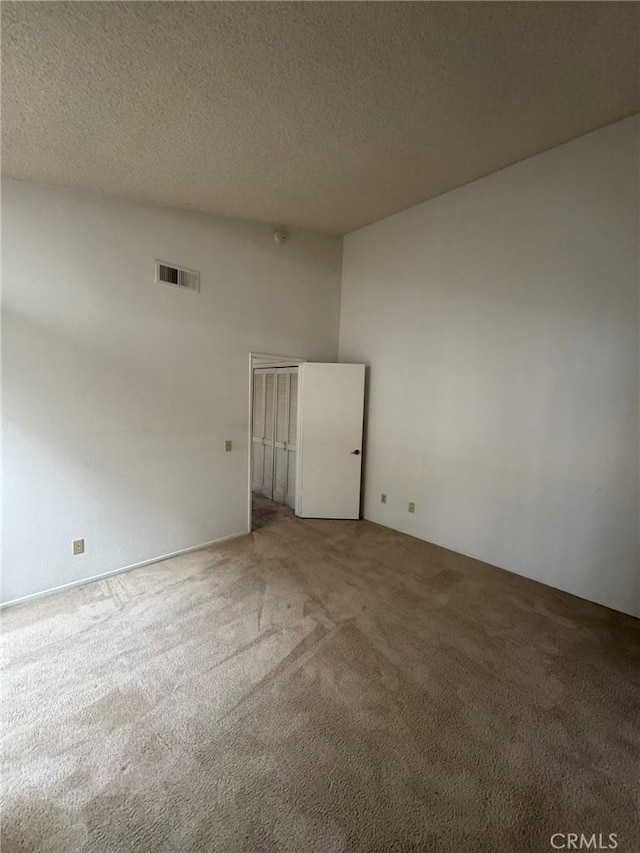 unfurnished room featuring a textured ceiling and carpet floors