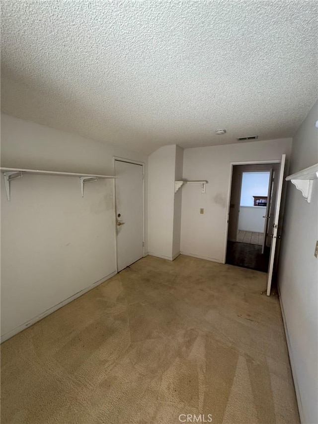 interior space with a textured ceiling and light carpet