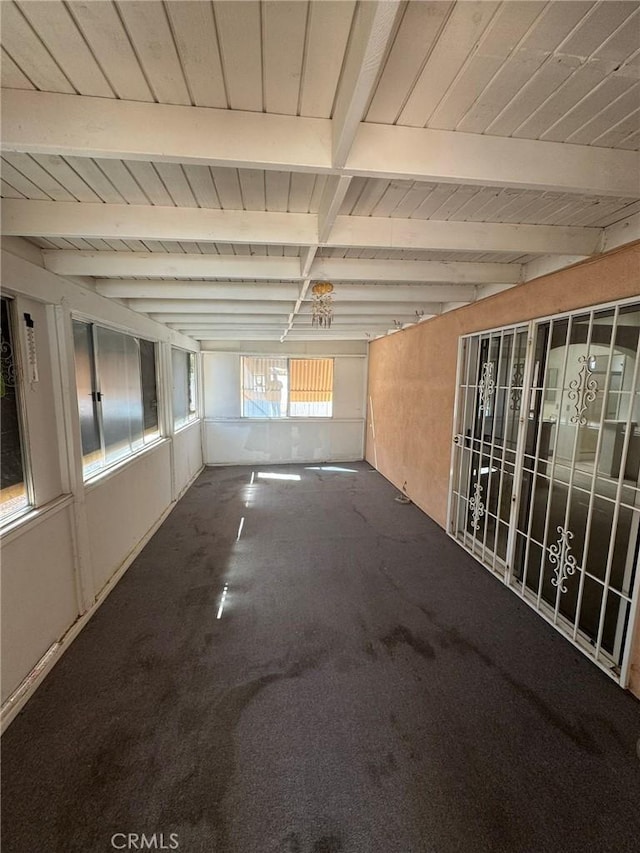 empty room featuring carpet, beamed ceiling, and wooden ceiling