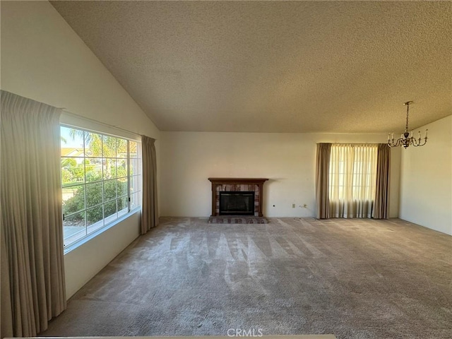 unfurnished living room with carpet, lofted ceiling, a fireplace, a textured ceiling, and a notable chandelier