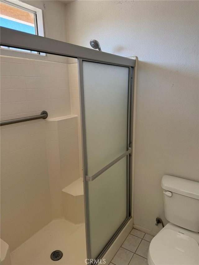 bathroom featuring tile patterned flooring, toilet, and walk in shower