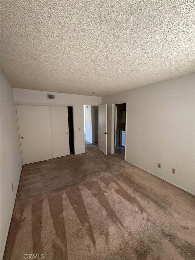 carpeted empty room featuring a textured ceiling