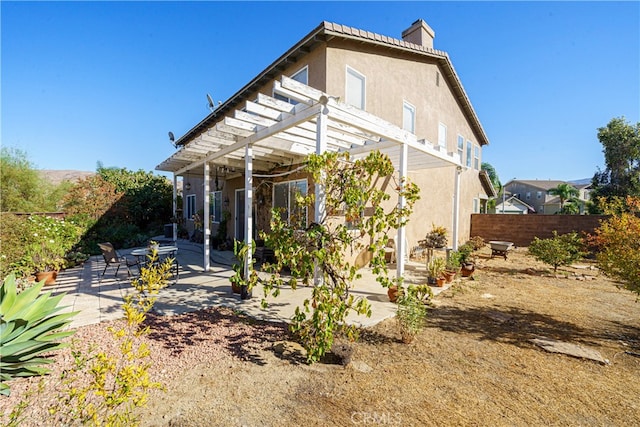 rear view of property featuring a pergola and a patio area