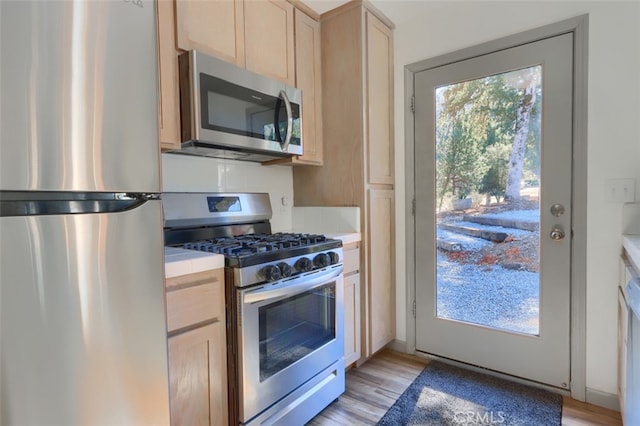 kitchen featuring stainless steel appliances, light brown cabinetry, and light wood-type flooring