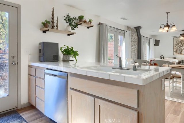 kitchen featuring light hardwood / wood-style floors, a healthy amount of sunlight, kitchen peninsula, and stainless steel dishwasher