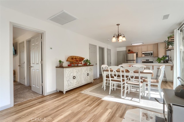 dining area with a notable chandelier and light wood-type flooring