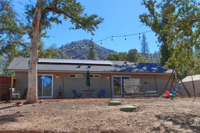 back of property featuring a mountain view and solar panels