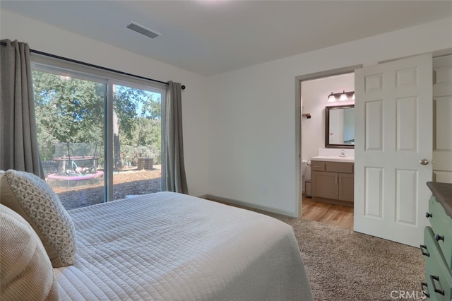 bedroom with ensuite bathroom, sink, and light hardwood / wood-style floors