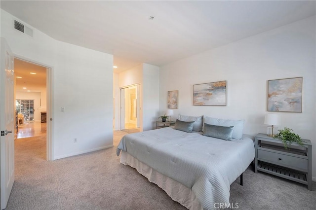 bedroom with light colored carpet and ensuite bath