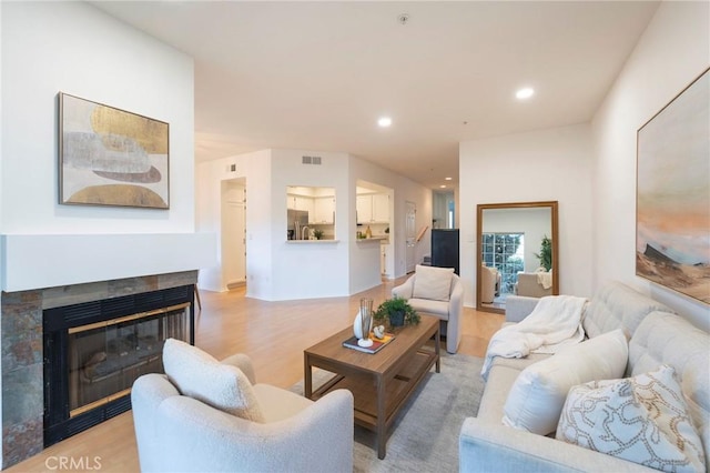 living room with a tiled fireplace and light hardwood / wood-style flooring