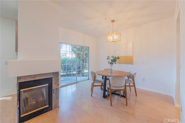 dining area featuring an inviting chandelier, a fireplace, and light wood-type flooring