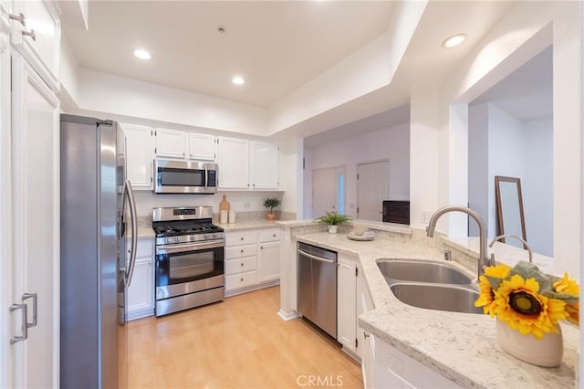 kitchen with light stone counters, sink, stainless steel appliances, and white cabinets