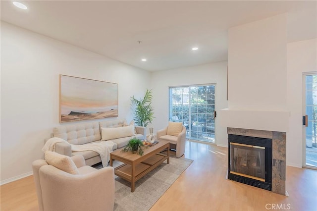 living room with a tile fireplace and light hardwood / wood-style flooring