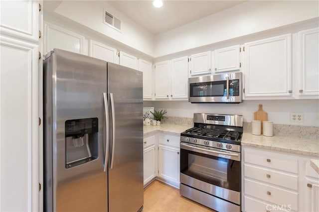 kitchen featuring white cabinetry, stainless steel appliances, light stone countertops, and light hardwood / wood-style floors