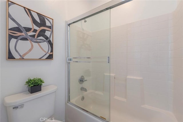 bathroom with toilet and combined bath / shower with glass door