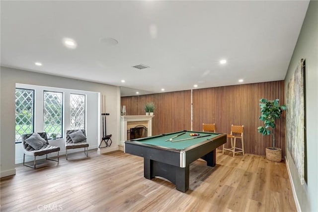 rec room with wood walls, light wood-type flooring, and pool table