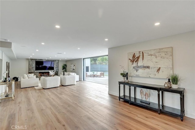 living room with expansive windows, a large fireplace, and light wood-type flooring