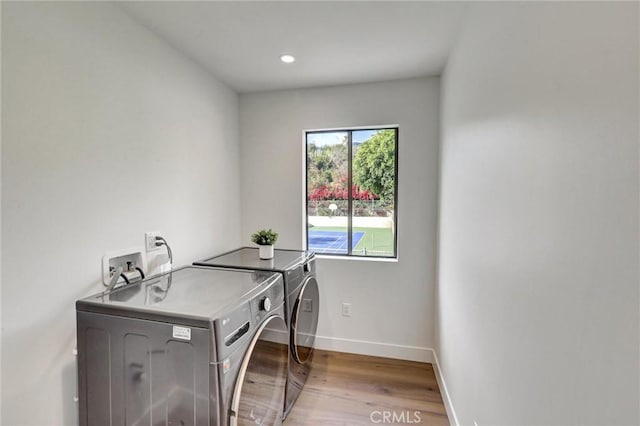 clothes washing area featuring separate washer and dryer and light hardwood / wood-style flooring