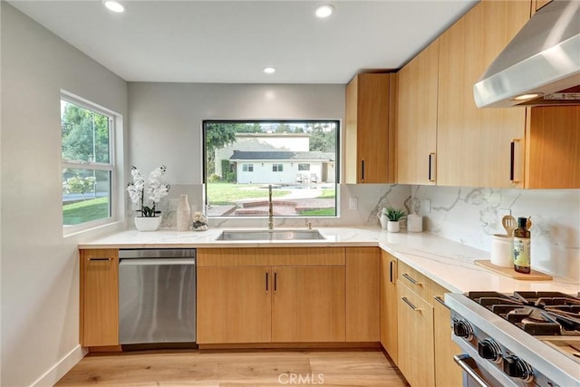 kitchen featuring light wood-type flooring, stainless steel appliances, sink, light brown cabinets, and range hood