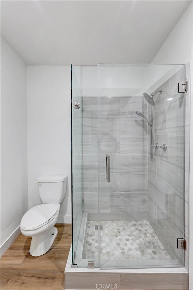 bathroom featuring wood-type flooring, toilet, and an enclosed shower