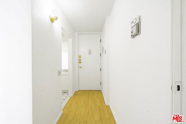 hall featuring light hardwood / wood-style floors and a textured ceiling