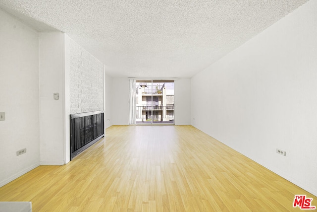 unfurnished living room with a fireplace, a textured ceiling, and light hardwood / wood-style flooring