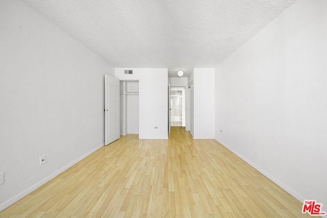 unfurnished bedroom with a closet, a textured ceiling, and light wood-type flooring