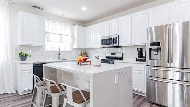 kitchen featuring a center island, white cabinets, light stone counters, appliances with stainless steel finishes, and dark hardwood / wood-style flooring