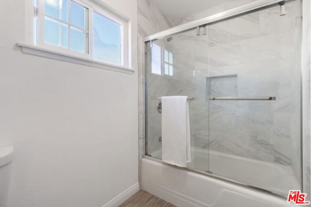 bathroom with toilet and combined bath / shower with glass door