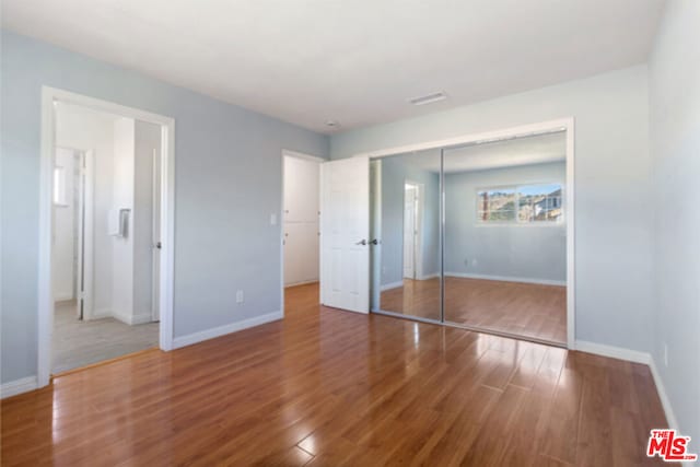 unfurnished bedroom with a closet and hardwood / wood-style floors