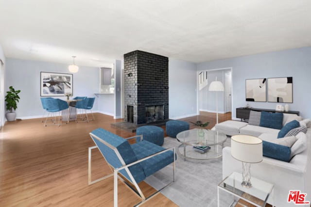 living room with hardwood / wood-style floors and a brick fireplace