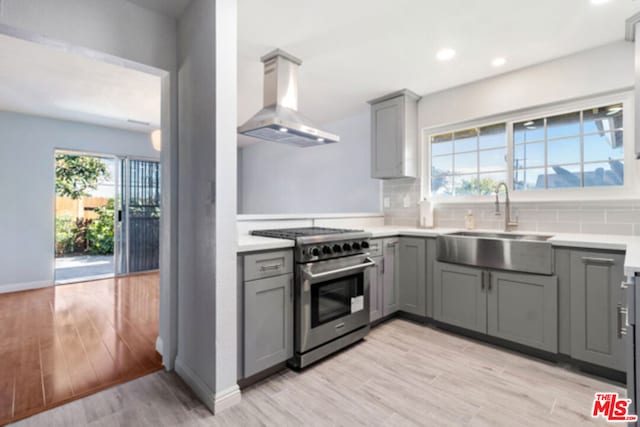 kitchen with stainless steel range, light hardwood / wood-style floors, a wealth of natural light, and range hood