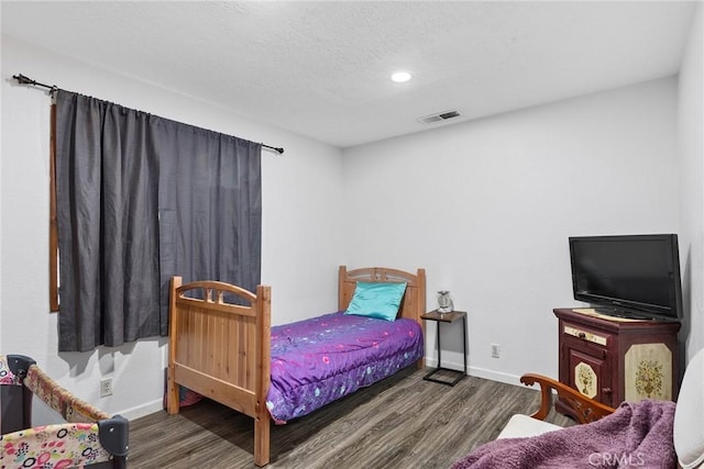 bedroom with a textured ceiling and dark hardwood / wood-style floors