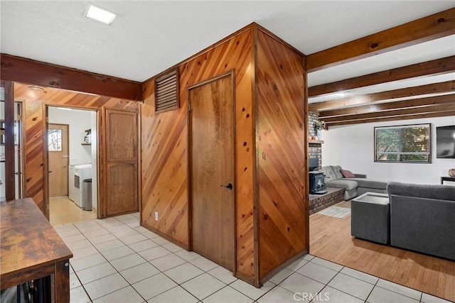 interior space with beam ceiling, light tile patterned floors, and wooden walls