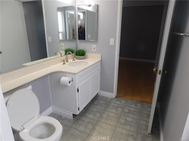 bathroom with toilet, vanity, and baseboards