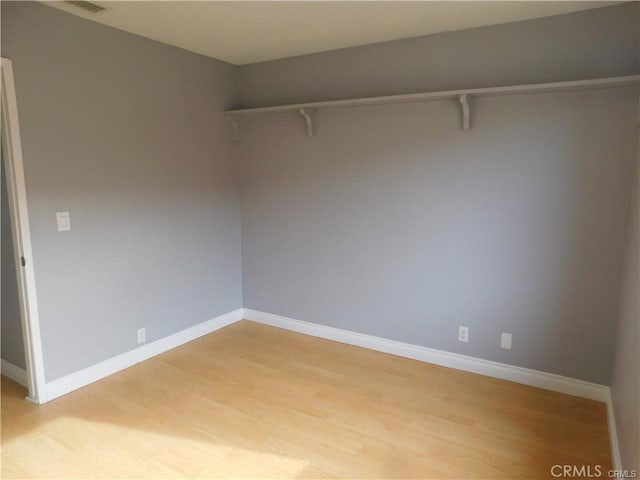 empty room featuring light wood-style floors, visible vents, and baseboards