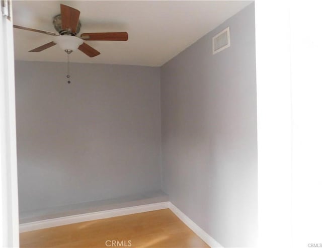 spare room featuring a ceiling fan, visible vents, light wood-style flooring, and baseboards