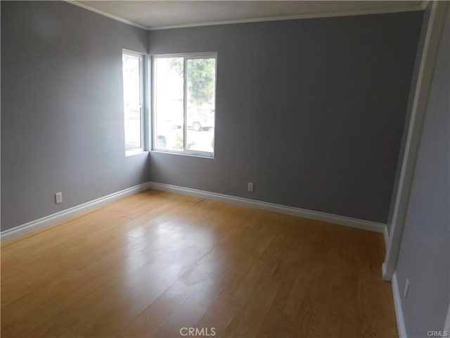 spare room with light wood-style floors, baseboards, and crown molding