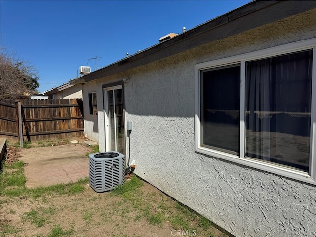 view of property exterior featuring central air condition unit, fence, a patio, and stucco siding