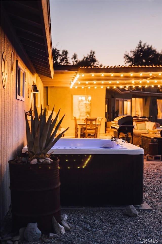 patio terrace at dusk featuring area for grilling and a hot tub