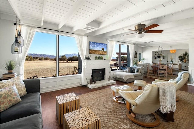 living room with ceiling fan, beamed ceiling, a healthy amount of sunlight, and dark hardwood / wood-style floors