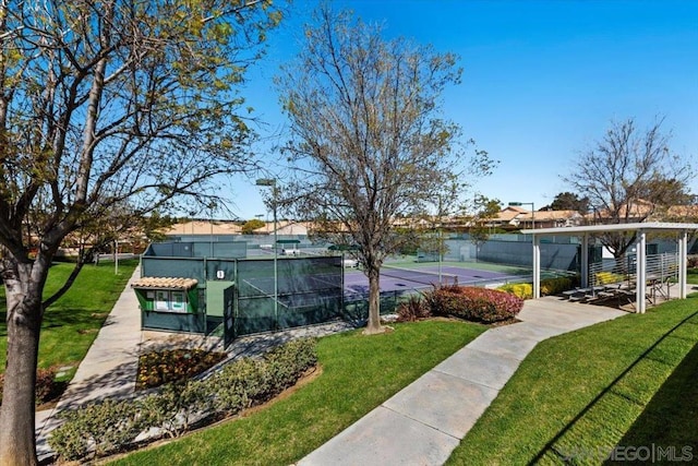 view of property's community featuring a lawn and tennis court