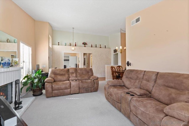 carpeted living room featuring a high ceiling, a fireplace, and an inviting chandelier